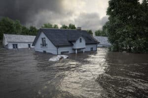 A house partially submerged in floodwaters, with dark clouds looming overhead.
