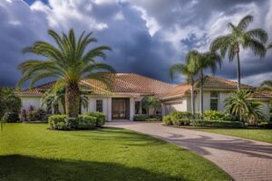 A Florida home with a tile roof and palm trees under a dramatic pre-storm sky