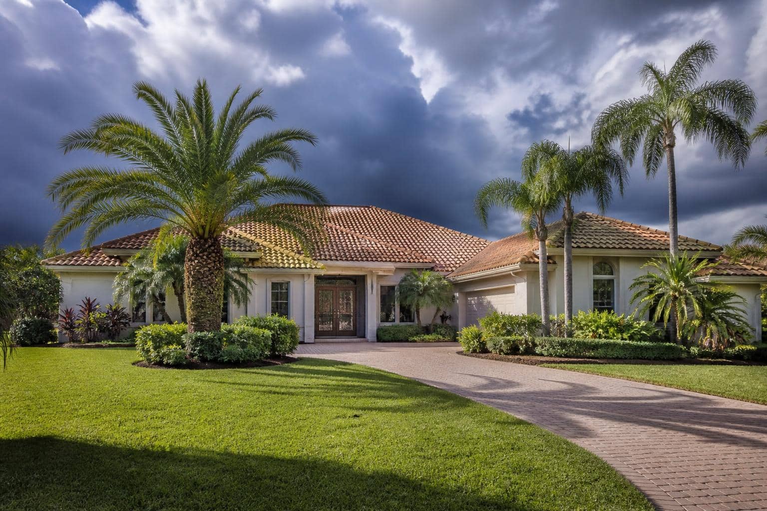 A Florida home with a tile roof and palm trees under a dramatic pre-storm sky